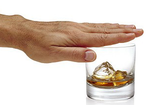 Man’s hand covering top of glass containing liquer and ice cubes.